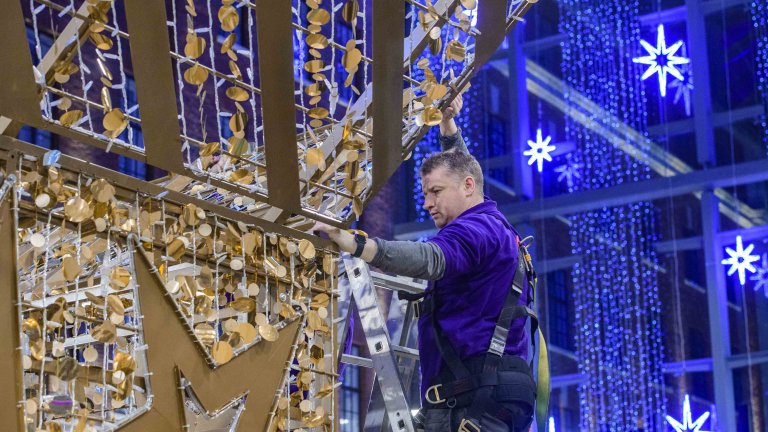 Chris Vaughan Photography - commercial photography | A worker installs gold star Christmas decorations in a shopping centre.