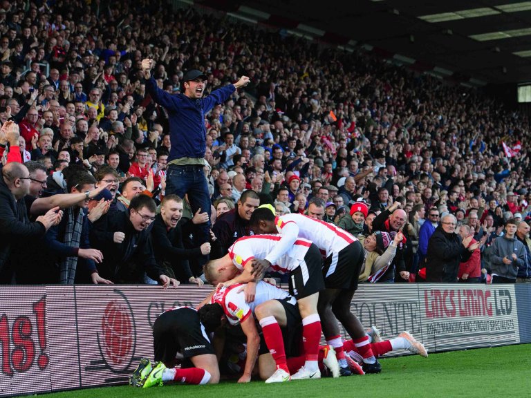 Chris Vaughan Photography - Sports images | Lincoln City players celebrate a late goal in front of a packed stand of fans.
