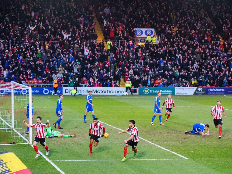 Chris Vaughan Photography - Sports images | Lincoln City's Lee Frecklington celebrates a goal with a stand full of fans in the background.