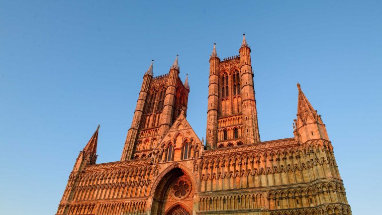 A photograph of the west front of Lincoln Cathedral as the sun starts to set.