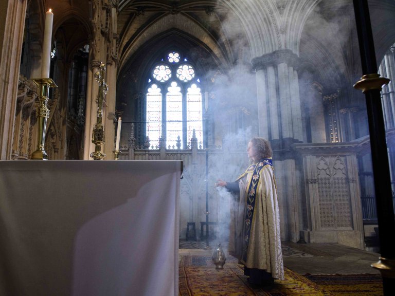 Chris Vaughan - case study images: Lincoln Cathedral | The Precentor is covered in smoke from the incense she is holding as she looks towards the alter.