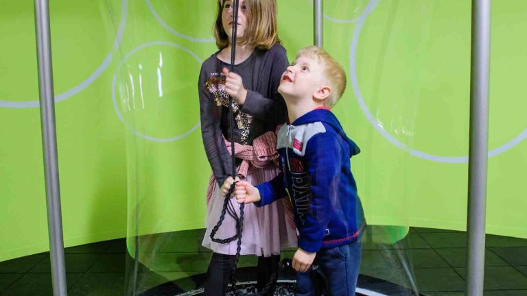Chris Vaughan - case study images: MathsCity | Two young children surround themselves with a giant bubble.