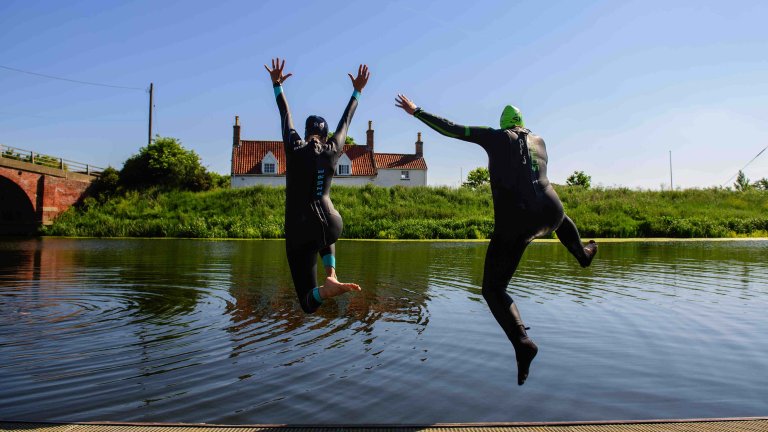 Chris Vaughan Photography - Sports images | Two open water swimmers jump into a river.