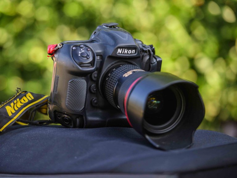 A photograph of a Nikon D5 camera sat on the top of a camera bag.