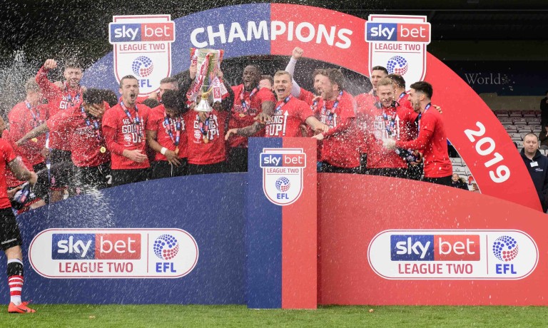Chris Vaughan Photography - case study: Lincoln City | Lincoln City players spray champagne as they celebrate with the EFL Sky Bet League Two trophy.