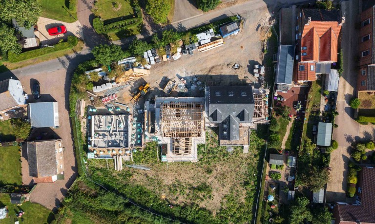 Chris Vaughan Photography - commercial images | A drone image looking down on three residential houses during various stages of construction.
