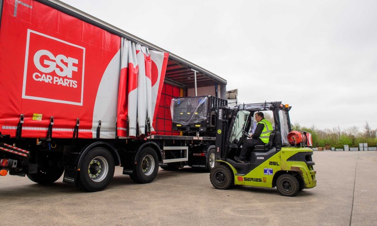 A GSF Car Parts colleague unloads items from a branded red lorry trailer using a forklift truck.