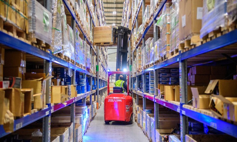 A member of the GSF Car Parts warehouse team uses a forklift truck to take items from a shelf.