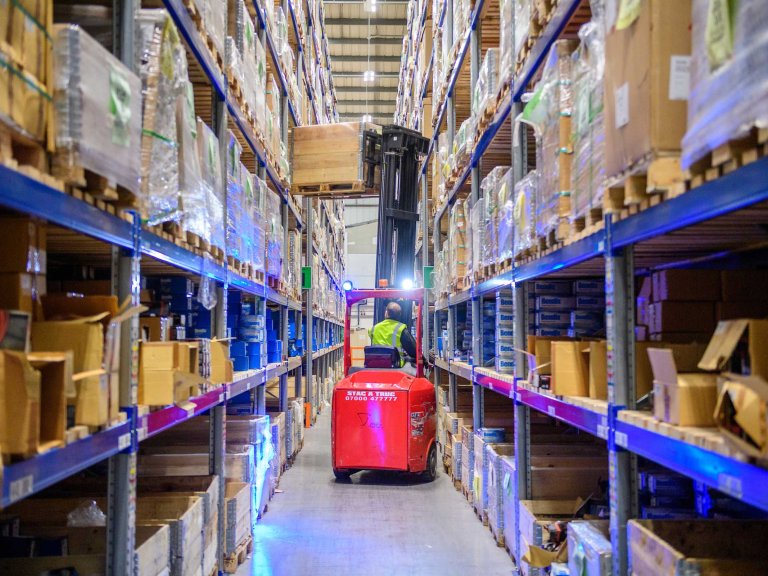 A member of the GSF Car Parts warehouse team uses a forklift truck to take items from a shelf.