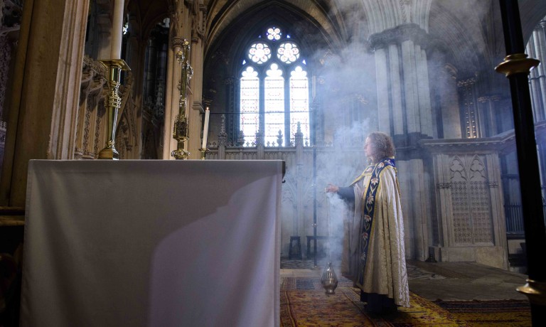 Chris Vaughan - case study images: Lincoln Cathedral | The Precentor is covered in smoke from the incense she is holding as she looks towards the alter.