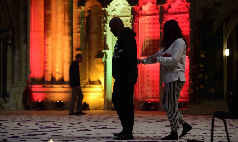 Chris Vaughan - case study images: Lincoln Cathedral | A couple lead each other around a labyrinth at night inside Lincoln Cathedral.